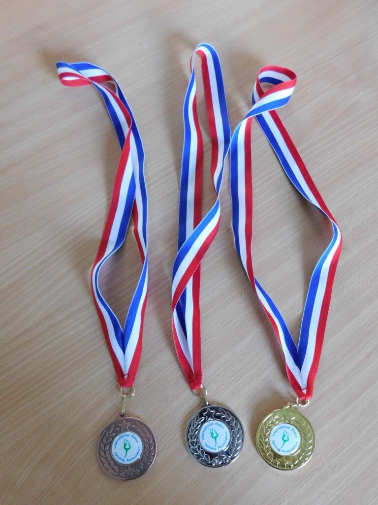 three sports medals on red, white and blue striped ribbons.