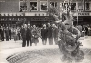 Black and white image of a group of people with a fountain in front of them.