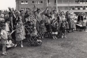 Black and white image of a group of people waving and holding flags