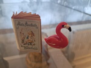 Photograph of small Alice in Wonderland book and pink flamingo toy.  