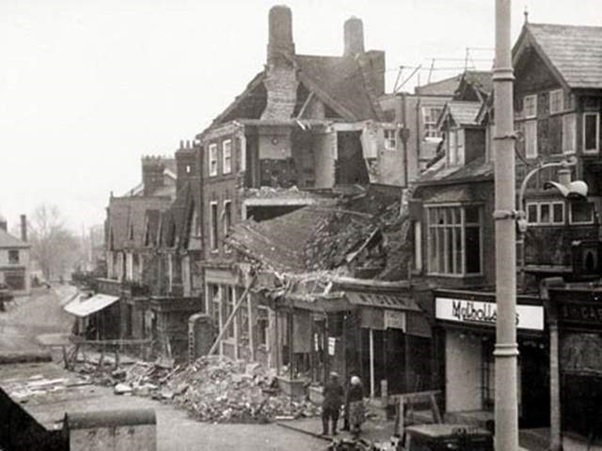 Black and white photograph of a row of building destroyed by a bomb. 