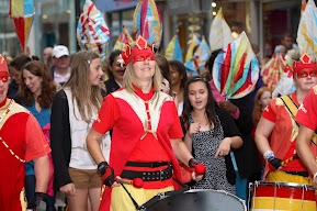 People in red outfits and drums with people behind them. 