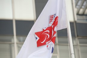 White flag with red, white and blue logo in the middle. 