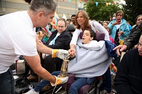 The flame in a gold lantern is held by members of the crowd. 