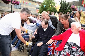 The flame in a gold lantern is held by members of the crowd. 