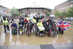 Group of people in wheel chairs gathered in a group and looking at the camera. 