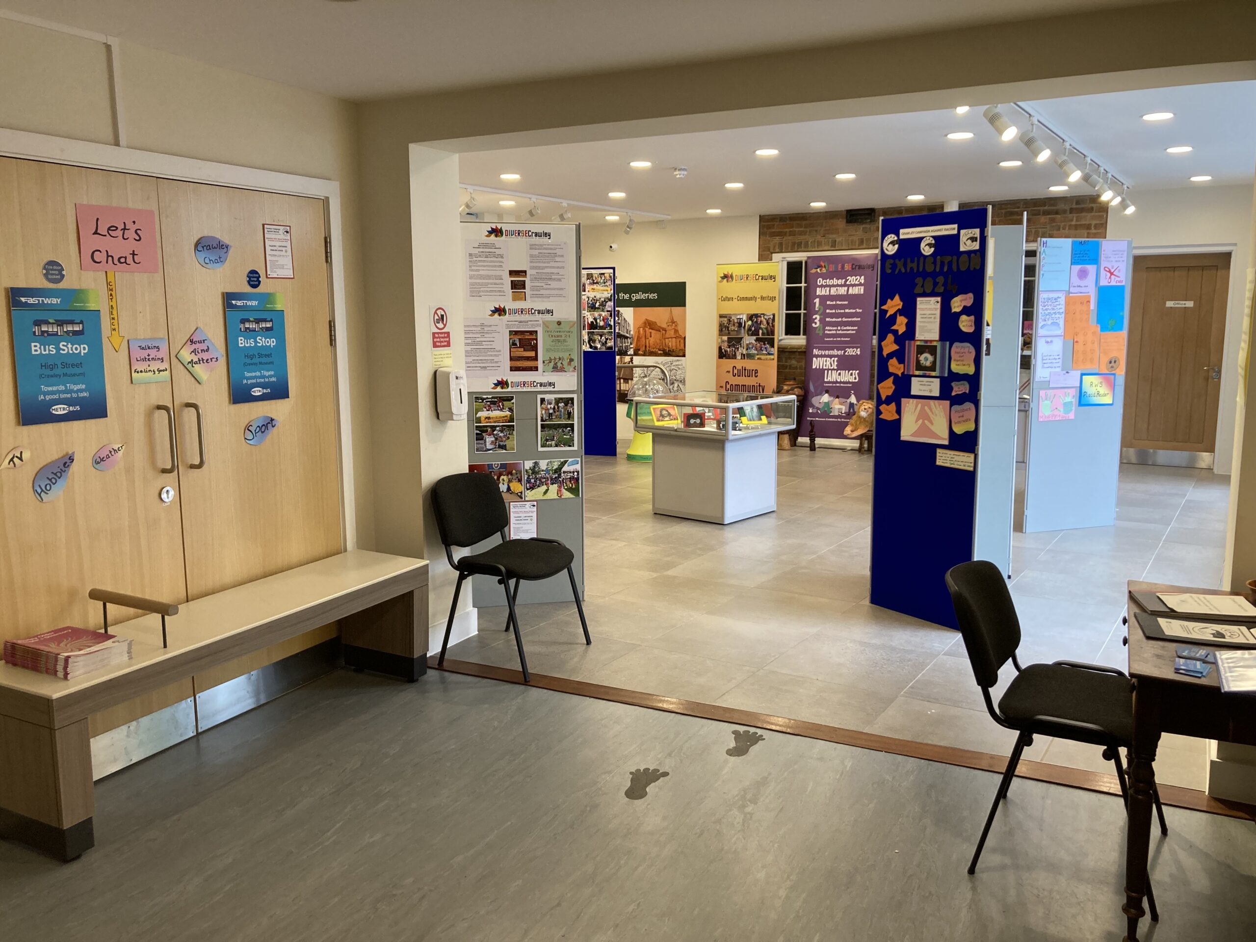 View of exhibition space from a distance, there are boards, display cases and seating dotted about.